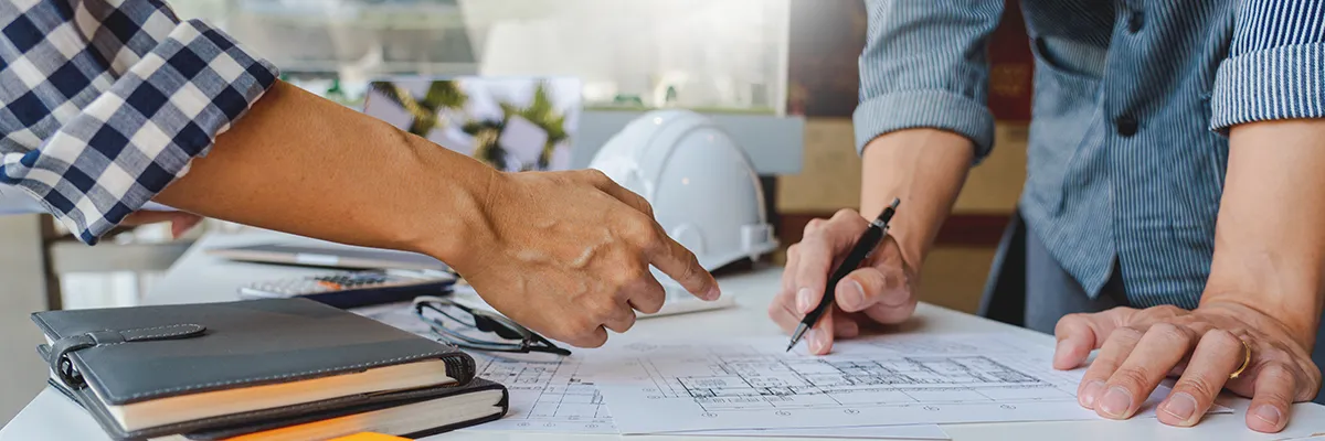 To personer studerer en hustegning.